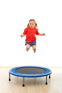 Little girl jumping on trampoline in gym - isolated, slight motion blur